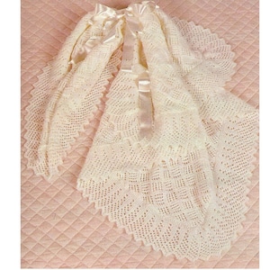 Peut inclure: Une couverture de bébé en crochet blanc avec un ruban de satin. La couverture présente un motif de dentelle délicat et est parfaite pour un nouveau-né.