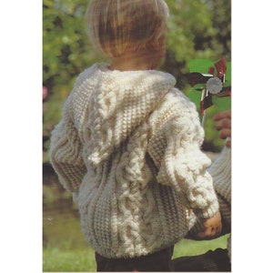 May include: A white knitted hooded sweater with a cable knit pattern. The sweater is worn by a child.
