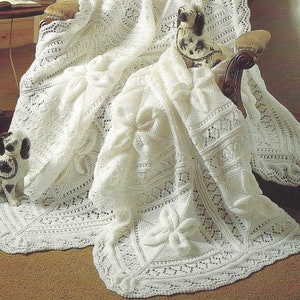 May include: A white crocheted blanket with a delicate lace pattern and large bows. The blanket is draped over a chair with a porcelain dog figurine on top.