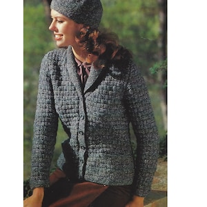 May include: A gray knitted cardigan with a collar and button closure. The cardigan has a textured pattern and is worn by a person with a gray beret.