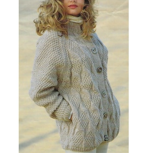 Könnte beinhalten: Ein beiger Strickcardigan mit Zopfmuster und Knopfleiste. Der Cardigan hat einen hohen Kragen und lange Ärmel.