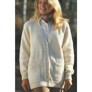 May include: A white knitted cardigan with a v-neck, long sleeves, and button closure. The cardigan has two pockets on the front and a ribbed hem and cuffs.