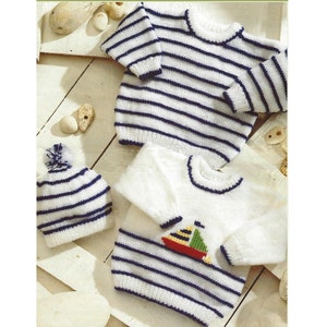 Op de afbeelding: Een set gebreide babykleding in een nautisch thema. De set bevat een witte trui met blauwe strepen en een klein zeilbootontwerp, een witte muts met blauwe strepen en een witte trui met blauwe strepen.