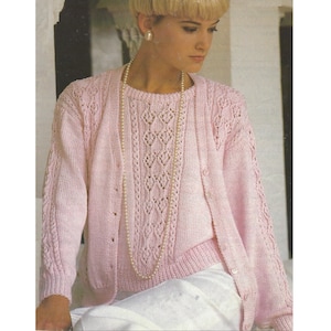 May include: A pink knitted cardigan and matching sweater set with a delicate lace pattern. The cardigan has a button closure and the sweater has a round neckline.