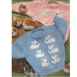 May include: Two knitted baby sweaters with bunny appliques. The sweater on the left is blue with five white bunnies. The sweater on the right is pink with three white bunnies.