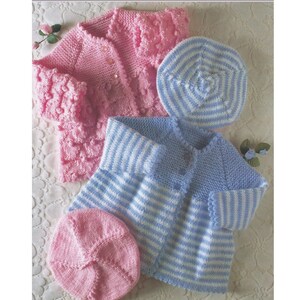 May include: Two knitted baby cardigans, one pink with a textured pattern and one blue with white stripes, and two matching knitted berets, one pink and one blue and white striped.