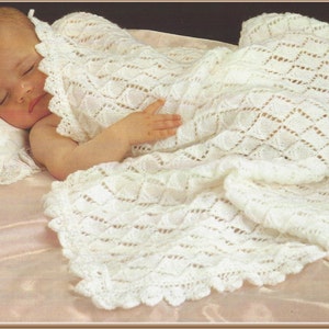 May include: A white crocheted baby blanket with a delicate lace pattern. The blanket is draped over a sleeping baby.