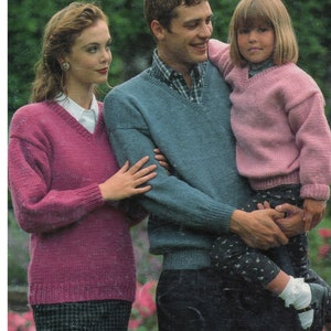 Puede incluir: Una familia lleva suéteres de punto a juego en rosa, azul y rosa claro. Los suéteres tienen cuello en V y mangas largas.