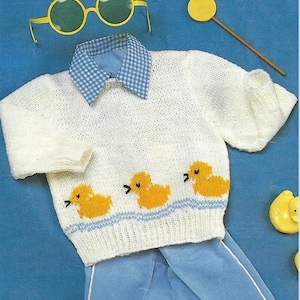 May include: A white knitted sweater with a blue and white checkered collar and a row of three yellow ducklings on the front.