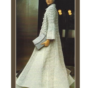 May include: A white crocheted coat with a long, flowing design. The coat has a button closure and a high collar.