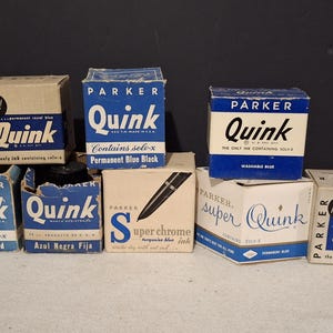 May include: A collection of vintage Parker Quink ink bottles in various colours, including blue, black, red, and turquoise. The bottles are labelled with the Parker Quink logo and the ink colour. Some bottles have the text "Contains sole-x" and "The only ink containing sole-x".