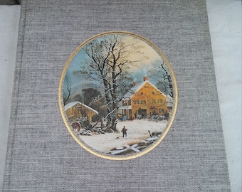 May include: A gray, textured book cover with a gold-framed illustration of a winter scene. The illustration depicts a small, yellow house with a snowy yard and a figure walking in the distance.