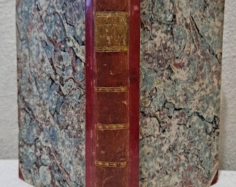 Op de afbeelding: Een vintage boek met een marmeren omslag en een rode rug. De titel op de rug is "Het leven en de avonturen van Robinson Crusoe".