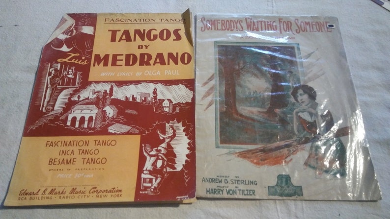May include: Two vintage sheet music covers. The left cover is red and yellow and features the text "Tangos by Medrano" with the song titles "Fascination Tango", "Inca Tango", and "Besame Tango". The right cover is white and features a woman in a forest setting with the text "Somebody's Waiting for Someone".
