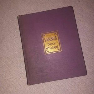 May include: A purple book with gold lettering on the cover. The title is "Verses" by "Dolf Wyllarde".