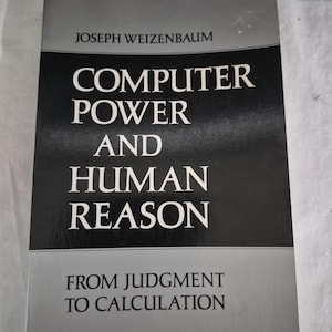 May include: A paperback book titled Computer Power and Human Reason: From Judgment to Calculation by Joseph Weizenbaum. The cover features a black central panel with white text, framed by grey sections at the top and bottom of the book cover.