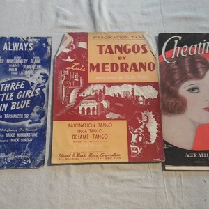 May include: Three vintage sheet music covers. The first cover is blue with the title "This Is Always" and features a photo of three women. The second cover is red and features the title "Tangos by Medrano" with a photo of a man in a suit. The third cover is red and features the title "Cheatin' On Me" with a photo of a woman with red hair.