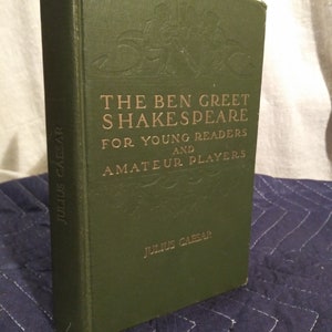 Puede incluir: Un libro verde con letras doradas titulado "The Ben Greet Shakespeare for Young Readers and Amateur Players" con la obra "Julius Caesar" listada debajo.