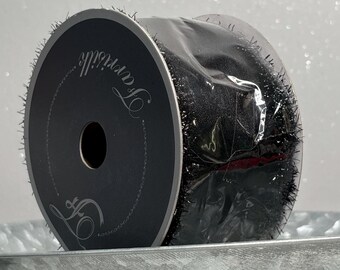 Peut inclure: Une bobine de ruban noir avec un bord effiloché et scintillant. La bobine est noire avec le mot "Larisilk" en écriture cursive. Le ruban est partiellement enveloppé dans du plastique transparent.