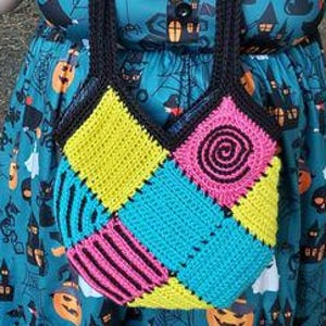 Könnte beinhalten: Handgefertigte gehäkelte Tragetasche mit einem Patchwork-Design. Die Tasche hat Quadrate in Gelb, Blau, Pink und Schwarz, mit einer schwarzen Spirale und gestreiften Details. Die Tasche hat schwarze Griffe.