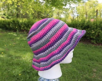 May include: A crocheted sun hat with wide brim in shades of pink, purple, and gray.