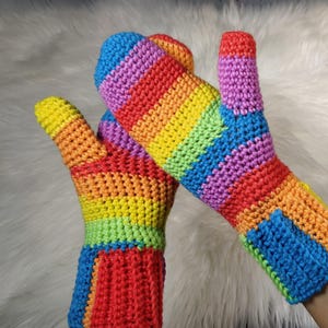 May include: A pair of rainbow striped crocheted mittens. The mittens are made with a variety of colors, including red, orange, yellow, green, blue, and purple.