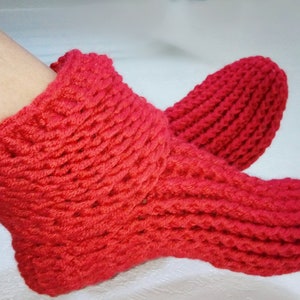 May include: A pair of red knitted slipper socks. The socks are made with a chunky yarn and have a ribbed texture.