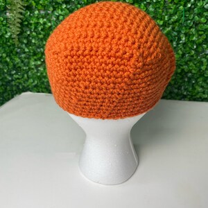 Op de afbeelding: Een feloranje gebreide beanie op een witte mannequinkop.