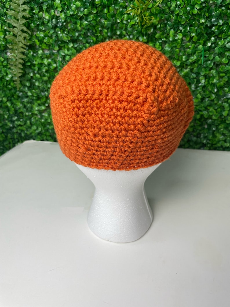 Op de afbeelding: Een feloranje gebreide beanie op een witte mannequinkop.