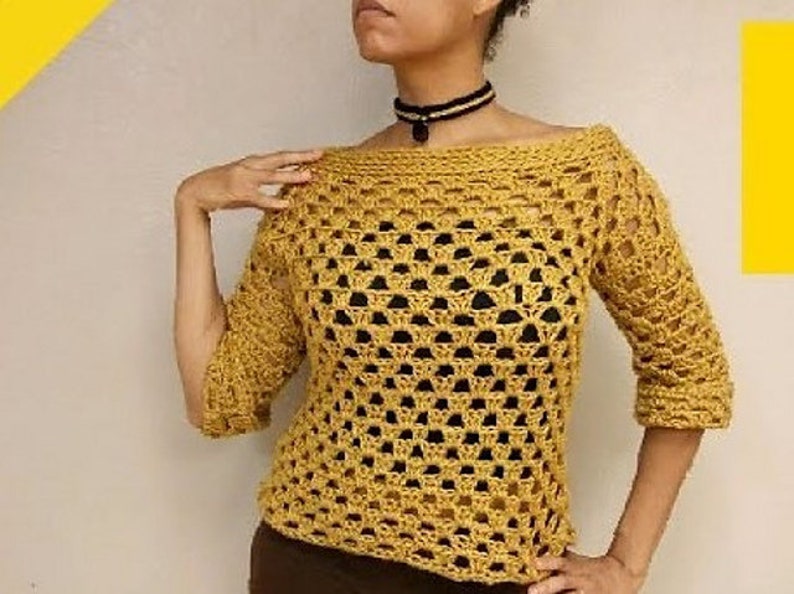 May include: A mustard yellow crochet top with a loose, open-weave design. The top has a wide, boat neckline and three-quarter sleeves.