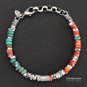 Op de afbeelding: Een armband met een mix van turquoise en oranje stenen kralen, afgewisseld met zilverkleurige metalen tussenstukjes. Het ontwerp bevat een karabijnsluiting, een ronde 925-keurmerklabel en een kettinggedeelte. De tekst 626elements JEWELLERY is zichtbaar.