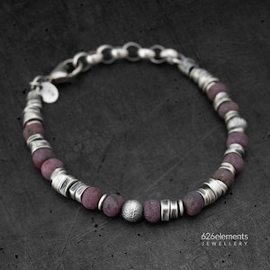 May include: A silver bracelet with a chain clasp and purple beads. The beads are interspersed with silver spacers. The bracelet has a textured silver bead in the center.