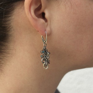 Peut inclure: Boucles d'oreilles pendantes en argent avec un groupe de petites pierres grises et de perles argent&eacute;es.