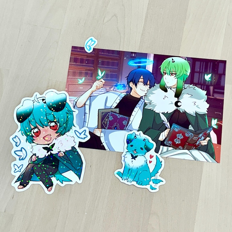May include: A collection of anime-style stickers and a print featuring two characters with blue and green hair. The print shows the characters reading books. The stickers include a chibi character and a dog, both in shades of blue.