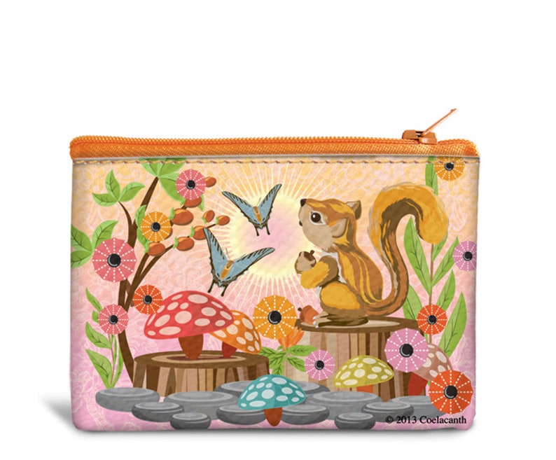 May include: A rectangular zippered pouch with a whimsical woodland scene. It features a cartoon squirrel holding a nut, butterflies, mushrooms, and flowers in shades of pink, orange, and green. The pouch has an orange zipper and trim.
