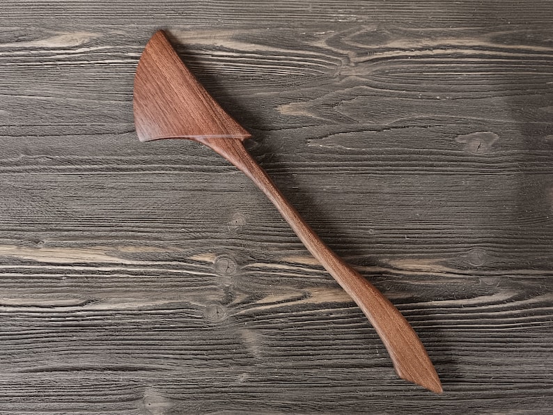 May include: A wooden spatula with a curved handle and a wide, flat blade. The spatula is made of dark brown wood and has a natural finish.