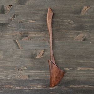 May include: A wooden spatula with a unique, curved design. The spatula is made of dark brown wood and has a smooth, polished finish.