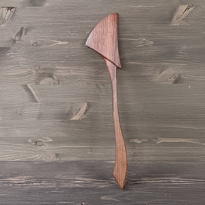 May include: A wooden spatula with a unique, curved handle. The spatula is made of dark brown wood and has a smooth, polished finish.