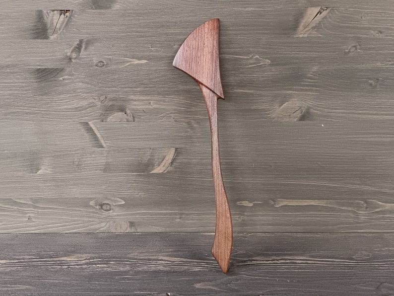 May include: A wooden spatula with a unique, curved handle. The spatula is made of dark brown wood and has a smooth, polished finish.