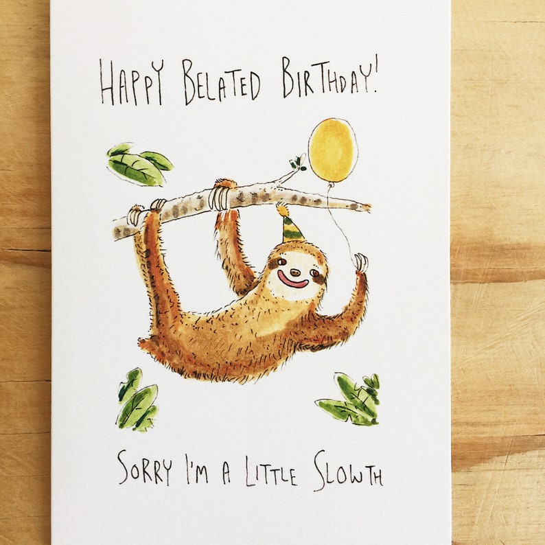 May include: A greeting card with a cartoon sloth wearing a party hat and holding a yellow balloon. The text on the card reads "Happy Belated Birthday! Sorry I'm a little sloth."