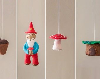 Puede incluir: Un conjunto de cinco adornos colgantes hechos de arcilla, que incluyen un gnomo sosteniendo un hongo, un hongo, una casa de tocón de árbol y dos bellotas. Los adornos están pintados en colores brillantes y tienen un tema caprichoso y boscoso.