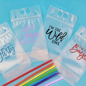 May include: Four clear plastic drink pouches with zipper closures and three holes for straws. Each pouch has a different phrase printed on it: "I'm the flirty one", "I'm the fun one", "I'm the wild one", and "I'm the boujee one".