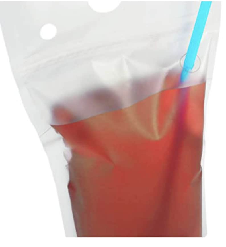 May include: A clear plastic pouch with a blue straw sticking out of the top. The pouch is filled with a red liquid.