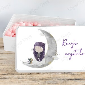 May include: White tin box with a purple and gray illustration of a girl and a dragon on a crescent moon. The text "Roxy's crystals" is written in purple on the box.