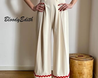 May include: White wide-leg pants with a high waist and red trim. The pants have a button closure and are made of a smooth fabric.