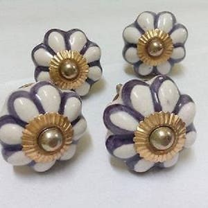 Pode incluir: Quatro botões de armário de cerâmica branca com listras roxas e detalhes dourados. Cada botão tem um design em forma de flor.