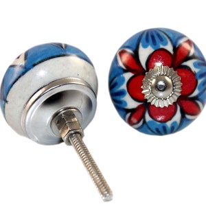 May include: Two decorative ceramic cabinet knobs. One knob features a blue and white floral design, while the other has a red and blue floral pattern. Both knobs have a silver metal base and screw for installation.
