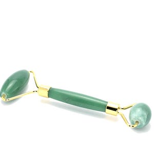 May include: A green jade roller with gold accents. The roller is designed for facial massage.