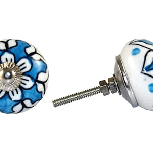 Pode incluir: Um botão de cerâmica azul e branco com um design floral. O botão está preso a um parafuso prateado.