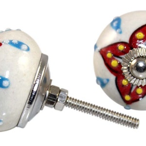 Può includere: Due pomelli per armadi in ceramica bianca con un design floreale rosso e giallo. Un pomello ha un motivo a pois blu e bianco. I pomelli hanno una vite in metallo argentato.